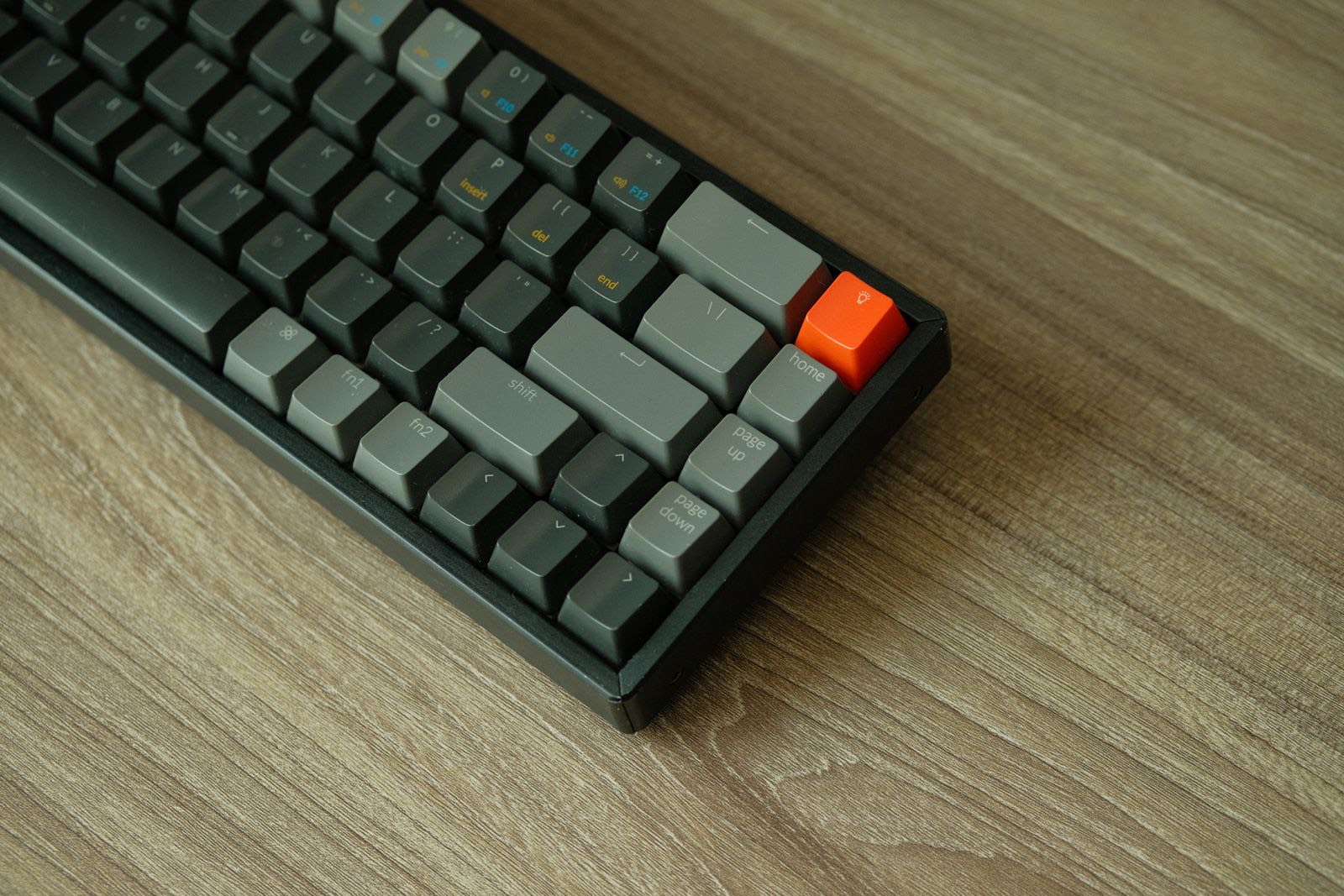 A mechanical keyboard with a single orange accent key on a warm wooden desk - a nod to giving each key its own job.