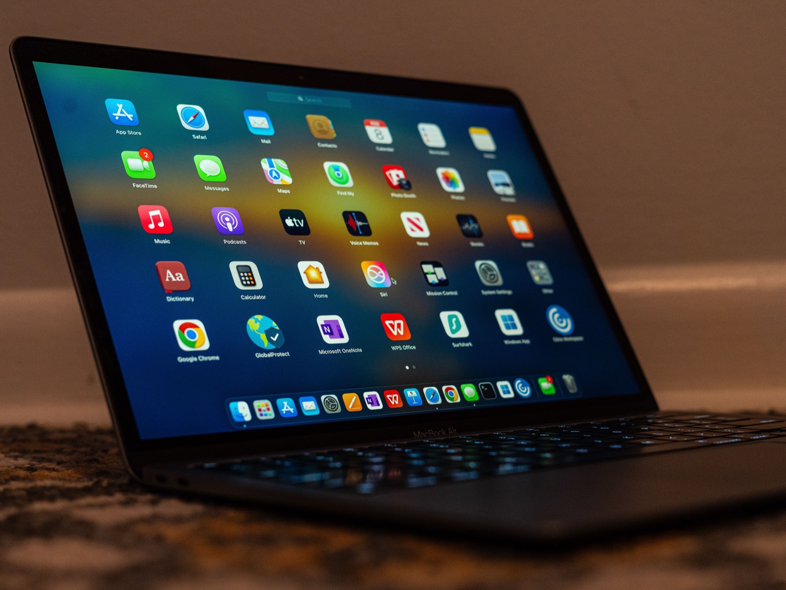 A MacBook on a warm wooden desk showing Launchpad - a full screen grid of app icons - a stand-in for the many Mac automation apps this guide compares.